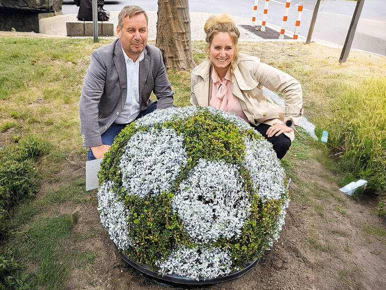 Bezirksbürgermeisterin Kirstin Bauch und der Vorsitzende der AG City, Uwe Timm, haben den kreativen Beitrag des bezirklichen Grünflächenamts zur UEFAEuro2024 auf dem Mittelstreifen des Kudamms enthüllt: ein Buchsbäumchen als Fußball. Foto: BACW