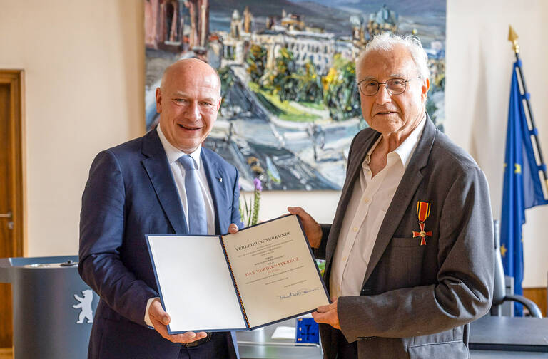 Kai Wegner übergibt Wolfgang Immenhausen das Verdienstkreuz am Bande. Foto: André Wunstorf / Landesarchiv Berlin